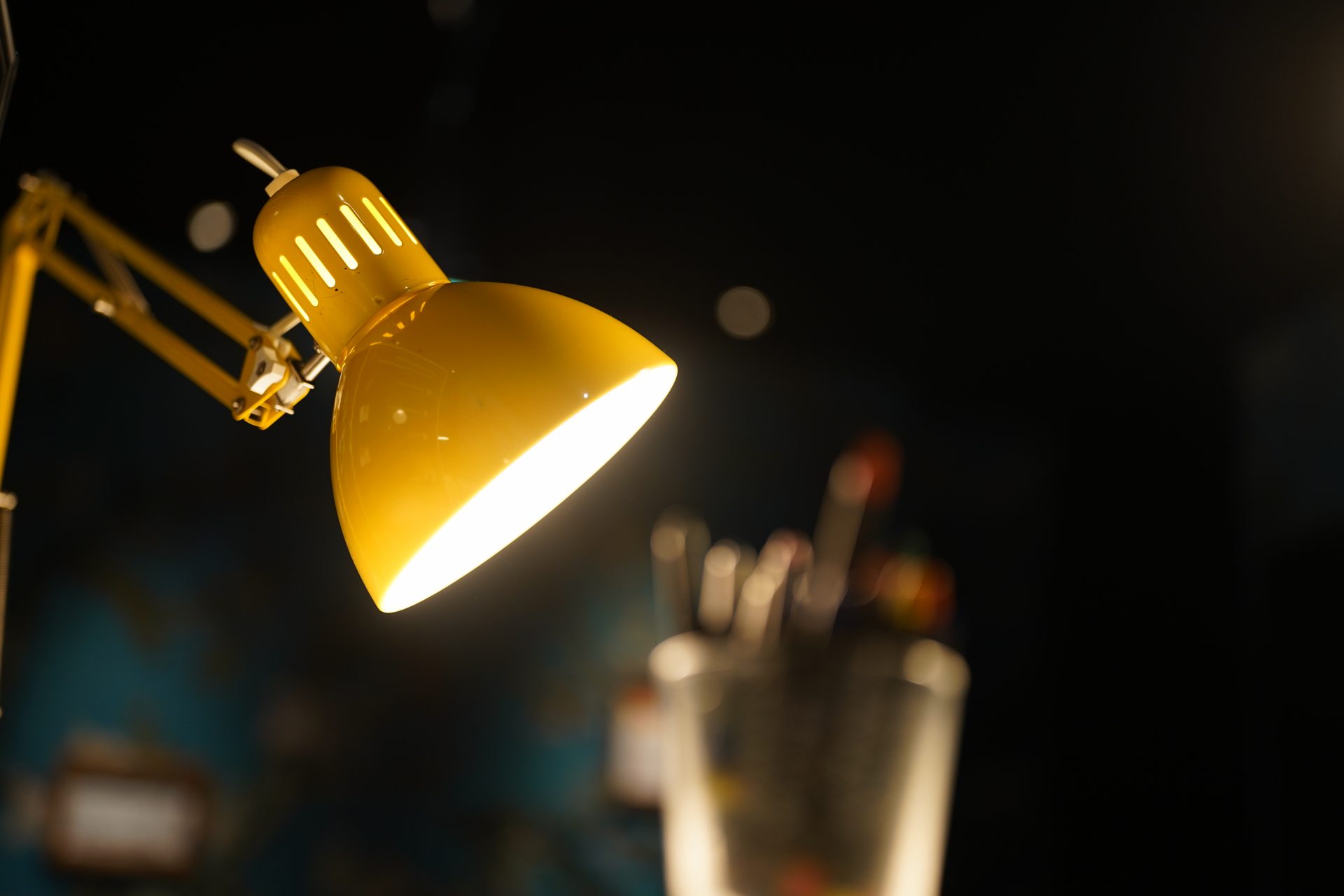 Gelbe Lampe leuchtet auf unscharfe Schreibutensilien im Hintergrund.