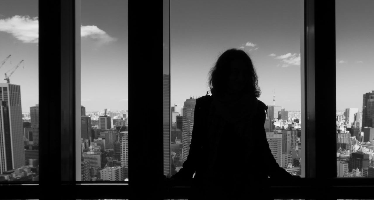 Schattenriss vor Fenster mit Aussicht auf städtische Skyline und Hochhäusern.